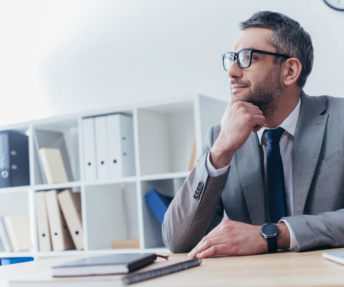 Man in business attire sat at desk looking satisfied