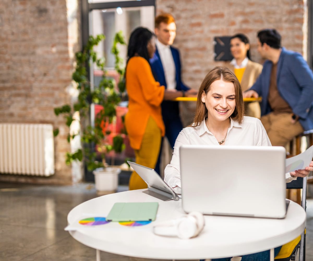 Woman using laptop and holding work documents